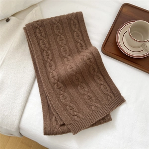 Gros plan sur la maille torsadée d'une écharpe en laine marron foncé au style hivernal