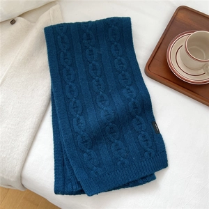 Gros plan d'une écharpe en laine bleu marine avec texture de tricot à mailles torsadées