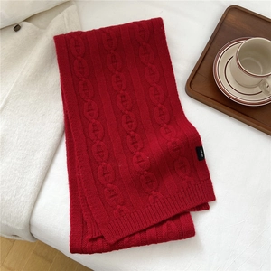 Détail d'une écharpe en laine rouge montrant la texture en tricot de chaîne premium