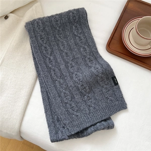 Détail d'une écharpe en tricot gris foncé 100% laine avec motif torsadé et étiquette