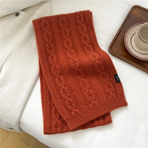 Détail de l'écharpe en tricot de laine rouge rouille avec étiquette de composition 100% laine