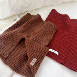Dettaglio di scaldacolli in maglia bordeaux e marrone con etichetta materiale 100% lana