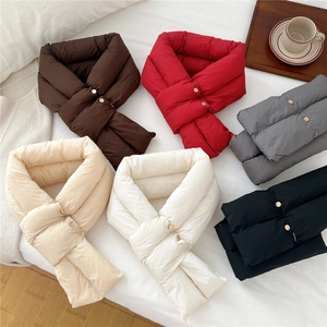 Padded cross scarves in six colors featuring gold buttons on a cozy white bed
