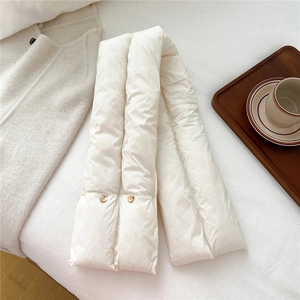 Close-up of white padded scarf with quilted sections and decorative gold buttons