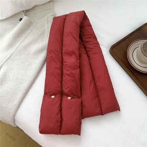 Detail of red quilted padded scarf featuring metal button closures on white bedding