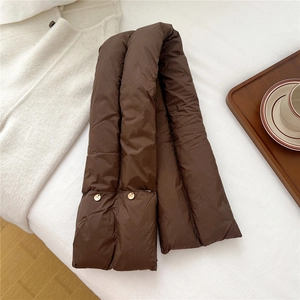 Detailed view of dark brown quilted down scarf with decorative gold metal brand tags
