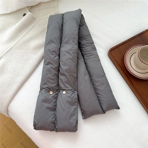 Detail of dark grey puffy scarf with metallic gold buttons on a warm cozy fabric background