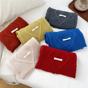 Chunky knit wool cross scarves in various vibrant colors with 100% wool label