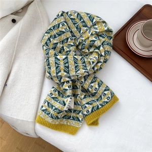 Détail de l'écharpe en maille jacquard géométrique avec motif jaune sur manteau blanc