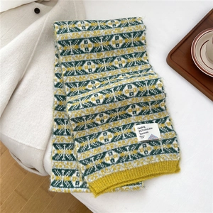 Gros plan d'une écharpe en tricot épaisse avec motif jacquard géométrique jaune et vert