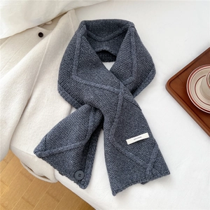 Detail of grey wool knit scarf with cable pattern and 100% wool material label