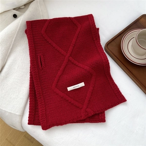 Detailed view of red 100% wool knit scarf featuring thick diamond texture and a cozy weave