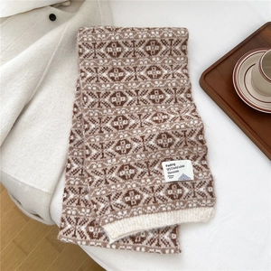 Détail d'une écharpe en maille épaisse avec motif jacquard et étiquette de marque