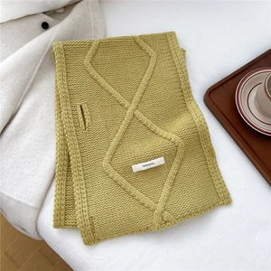 Detailed macro view of mustard yellow cable knit wool scarf with 100% wool label