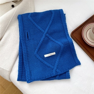 Detailed texture of royal blue wool scarf with diamond knit pattern and 100% wool tag