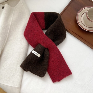 Close-up of a red and brown knit scarf featuring a white woven BOOM PLAN brand tag