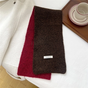 Detailed knit texture of a dual-tone winter scarf featuring a white BOOM PLAN woven label