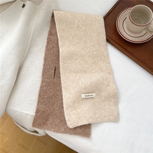 Close-up of beige and brown knitted scarf with a woven label and cross-hole design