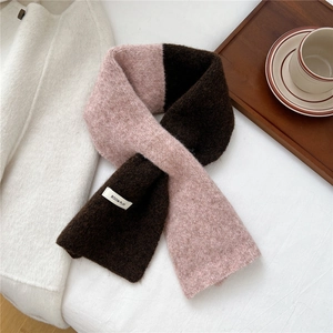 Close-up of pink and brown knitted scarf with woven label on a wooden tray with coffee
