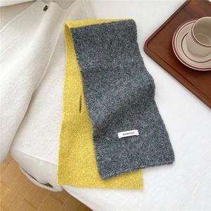 Detail of cross-knit scarf with BOOM PLAN label and yellow-grey color block design