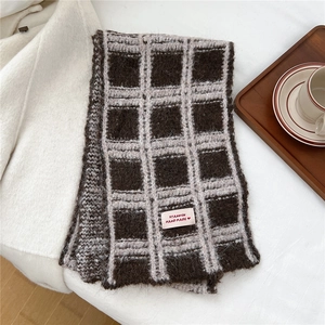 Macro di una sciarpa in maglia a quadri marroni con etichetta rosa e decorazione in legno