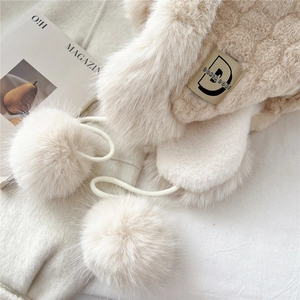 Close-up of plush thermal earflap hat with soft pom-poms and brand label detail