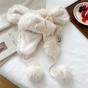 Detail of plush winter trapper hat with cute large animal ears and white fluffy pom-poms