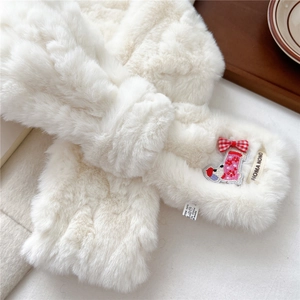 Close-up of a plush beige scarf with dog embroidery and 100% polyester material label