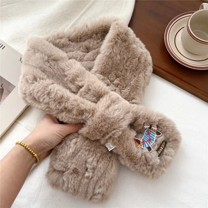 Detail of soft khaki plush scarf with embroidered dog patch and cross-hole design