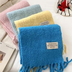 Close-up of thick knitted scarves with fringes and woven labels in vibrant colors