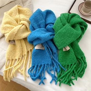 Minimalist thick knit scarf with fringe and brand label in yellow, blue, and green colors