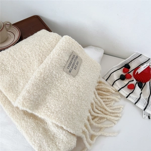 Close-up of beige knit scarf with textured boucle yarn and stylish long fringe