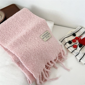 Close-up of pink thick knit scarf showing soft texture, long tassels and woven label
