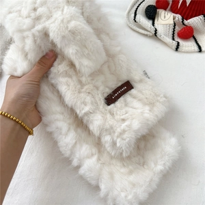 Close-up of soft white faux fur scarf texture and rectangular brand logo patch