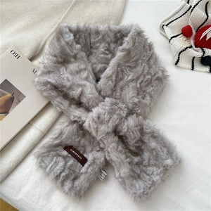 Close-up of light gray faux fur scarf showing cross design and premium material labels