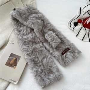 Detailed view of grey faux fur scarf texture with brown branded leather logo patch