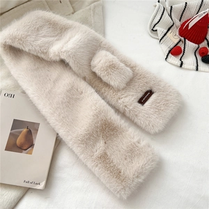 Detail of beige faux fur scarf with soft texture and leather brand label on white fabric