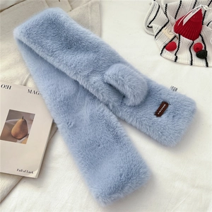 Detail of light blue faux fur scarf featuring a brown leather logo and cross-over design