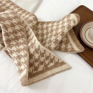 Detail of soft houndstooth knitted scarf texture with classic brown and beige patterns