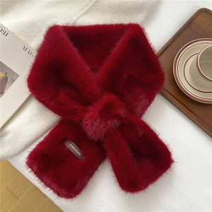Detail of dark red faux fur scarf with cross-over design and brand label on soft knit