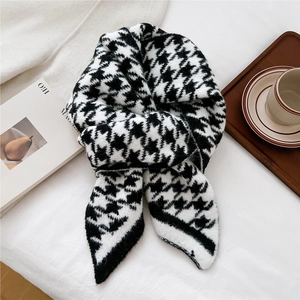 Detailed close-up of houndstooth knit scarf with chic pointed ends in a cozy setting