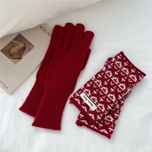 Close-up of deep red knitted winter gloves with white geometric patterns and ribbed cuffs