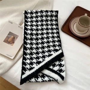 Detail of classic black and white houndstooth knit scarf with soft fringe texture