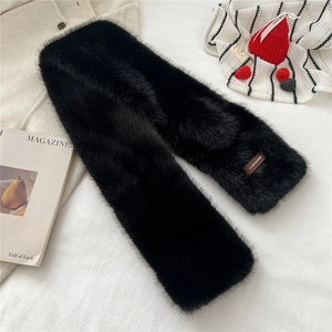 Detail of soft black faux fur scarf with brand label on cozy winter knitted fabric