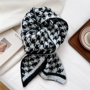 Detail of classic black and white houndstooth knit scarf in a cozy lifestyle setting