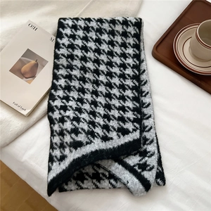 Detailed view of soft houndstooth knit scarf texture on a minimalist wooden tray
