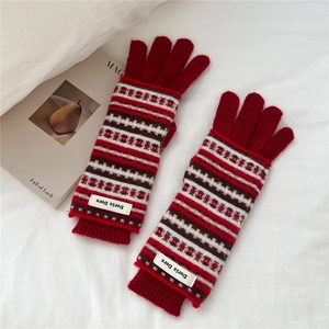 Close-up of red knit mittens with vintage jacquard patterns and ribbed cuff details