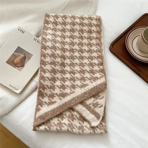 Detail shot of the thick houndstooth knit scarf texture in brown and beige tones
