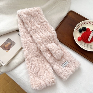 Detail of light pink plush scarf showing soft ripple texture and brand woven label