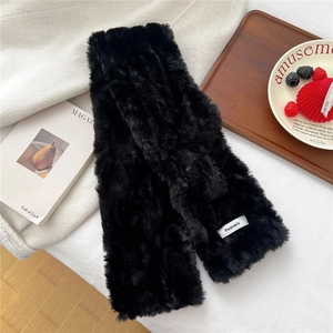 Detailed close-up of soft black faux fur scarf featuring a premium woven brand label
